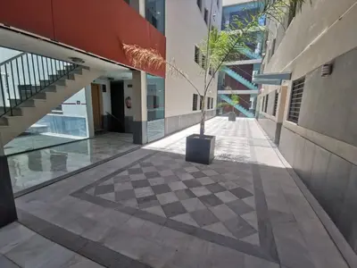 a courtyard with a potted tree in the middle of a building at La Gema de La Caleta in Cádiz