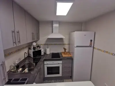 a kitchen with a white refrigerator and a sink at La Gema de La Caleta in Cádiz