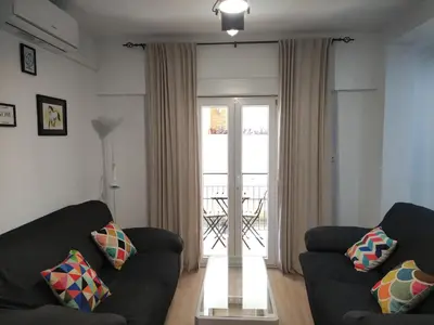 a living room with two black couches and a balcony at El pisito Sanlúcar in Sanlúcar de Barrameda