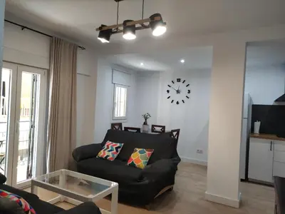 a living room with a couch and a clock on the wall at El pisito Sanlúcar in Sanlúcar de Barrameda