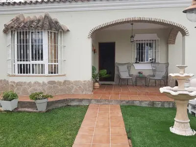 a white house with a patio with chairs and a fountain at Casa El Veranito in Chiclana de la Frontera