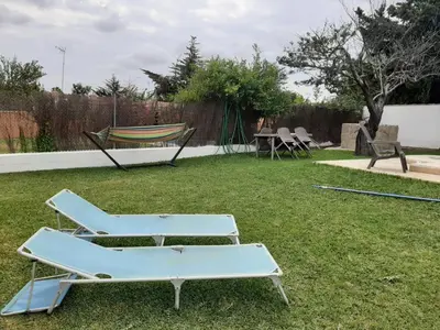 two chairs and a hammock in a yard at Casa El Veranito in Chiclana de la Frontera