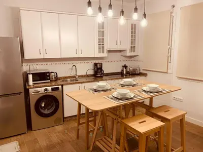 a kitchen with white cabinets and a table with chairs at Chipiona Acogedor LA in Chipiona