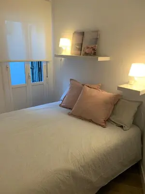 a bedroom with a bed with two pillows and two lamps at Chipiona Acogedor LA in Chipiona