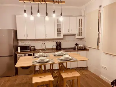 a kitchen with white cabinets and a wooden table at Chipiona Acogedor LA in Chipiona