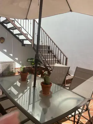 a glass table with two chairs and an umbrella at MyChoice Blas Infante in Rota
