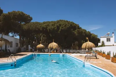 a large swimming pool with chairs and umbrellas at TAIGA Conil in Conil de la Frontera