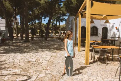 a young girl holding a skateboard in a park at TAIGA Conil in Conil de la Frontera