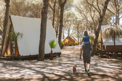 a man with a child on his back walking a dog at TAIGA Conil in Conil de la Frontera