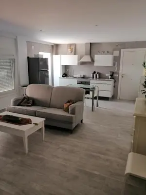 a living room with a couch and a kitchen at Hormaza Chiclana in Chiclana de la Frontera