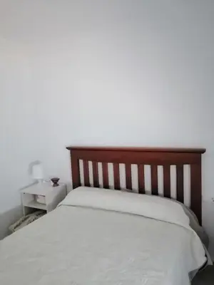 a bedroom with a white bed with a wooden headboard at Hormaza Chiclana in Chiclana de la Frontera