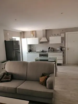 a living room with a couch and a kitchen at Hormaza Chiclana in Chiclana de la Frontera