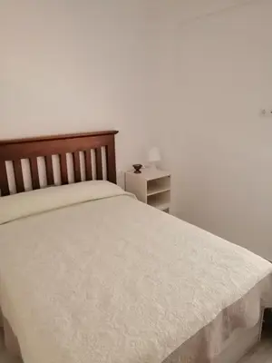 a bedroom with a white bed with a wooden headboard at Hormaza Chiclana in Chiclana de la Frontera