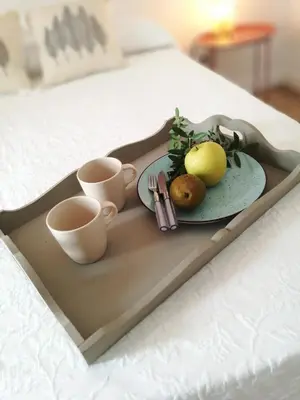a tray with a plate of fruit and cups on a bed at MEDINA BLUE - CASITAS CON ENCANTO in Medina Sidonia
