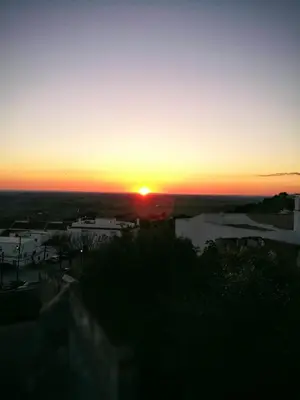 a sunset over a city with the sun setting at MEDINA BLUE - CASITAS CON ENCANTO in Medina Sidonia