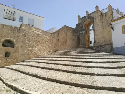 an old building with stone steps next to a wall at MEDINA BLUE - CASITAS CON ENCANTO in Medina Sidonia
