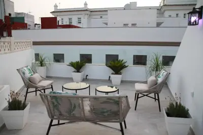 a patio with chairs and tables on a building at Luz, aire y mar Grupo AC Gestion in Cádiz