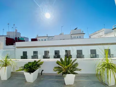 a white building with potted plants in front of it at Luz, aire y mar Grupo AC Gestion in Cádiz
