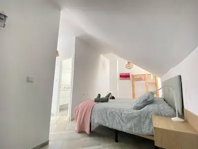 a bedroom with a bed in a white room at Buhardilla en calle Ancha, pleno centro in Sanlúcar de Barrameda
