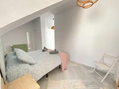 a bedroom with a bed and a chair at Buhardilla en calle Ancha, pleno centro in Sanlúcar de Barrameda