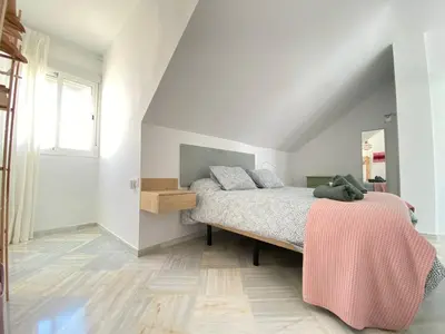 a bedroom with a bed with a pink blanket on it at Buhardilla en calle Ancha, pleno centro in Sanlúcar de Barrameda