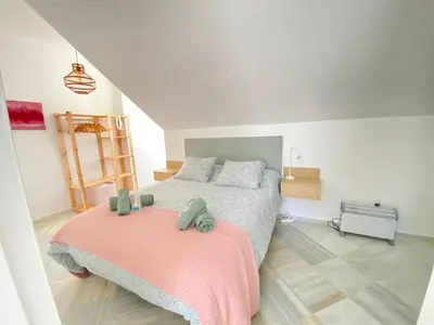 a bedroom with a bed with a pink blanket at Buhardilla en calle Ancha, pleno centro in Sanlúcar de Barrameda