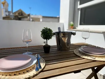 a wooden table with two glasses and a plate of food at Buhardilla en calle Ancha, pleno centro in Sanlúcar de Barrameda