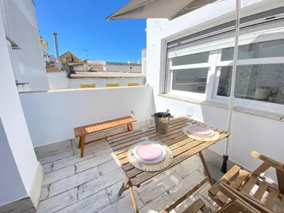 a patio with a wooden table and a bench at Buhardilla en calle Ancha, pleno centro in Sanlúcar de Barrameda