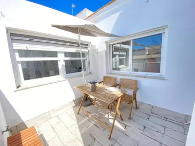a patio with a table and chairs and an umbrella at Buhardilla en calle Ancha, pleno centro in Sanlúcar de Barrameda