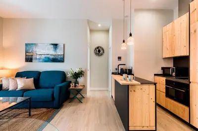 a living room with a blue couch and a kitchen at Genteel Home Sagasta in Cádiz