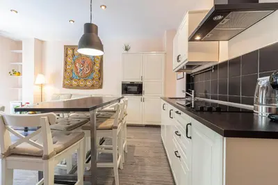 a kitchen with white cabinets and a table and chairs at Allo Apartments Plateros II Centro 2 Habitaciones in Jerez de la Frontera