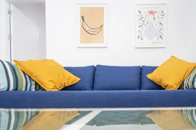 a blue couch with yellow pillows in a living room at Apartamento Ooh La Lá Cádiz in Cádiz