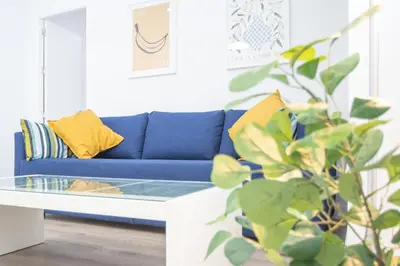 a blue couch in a living room with a glass table at Apartamento Ooh La Lá Cádiz in Cádiz