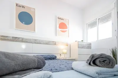a white bedroom with two beds with towels on them at Apartamento Ooh La Lá Cádiz in Cádiz