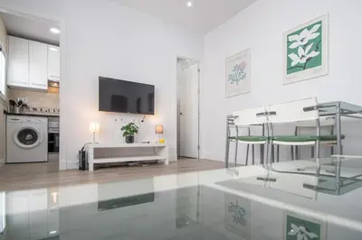 a white living room with a tv on a wall at Apartamento Ooh La Lá Cádiz in Cádiz