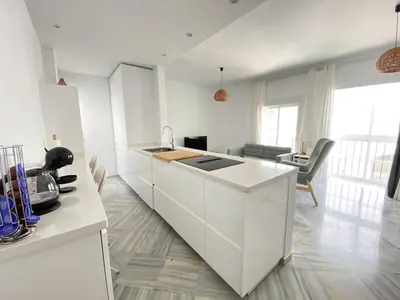 a kitchen with white cabinets and a living room at Apartamento en calle Ancha, en pleno centro in Sanlúcar de Barrameda