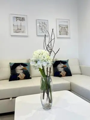 a vase with white flowers on a table in front of a couch at GATU PREMIUM Alma marinera, Preferente mayores de 21 años y familias in Cádiz