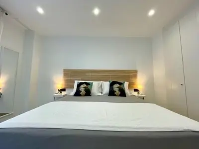 a white bedroom with a large bed with two dogs on the pillows at GATU PREMIUM Alma marinera, Preferente mayores de 21 años y familias in Cádiz