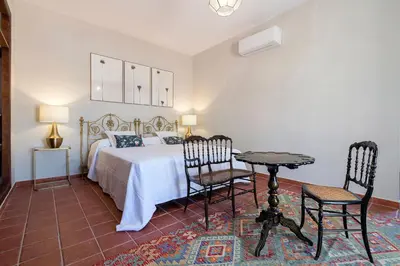 a bedroom with a bed with two chairs and a table at Cortijo La Mina by LaJudería de Vejer - Luxury Villa in Conil de la Frontera