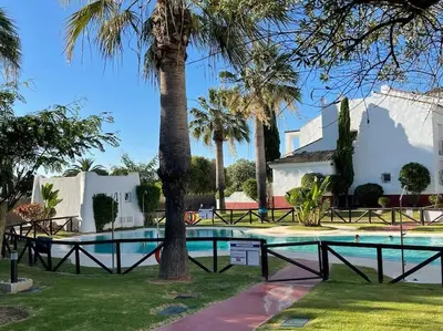 a swimming pool with a palm tree next to a house at Costa Ballena Unifamiliar in Costa Ballena
