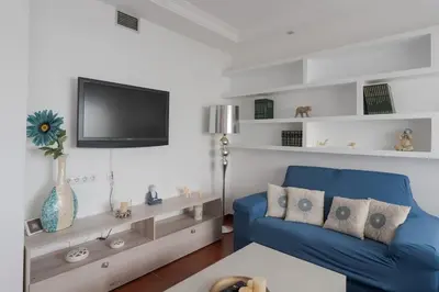 a living room with a blue couch and a tv at Costa Ballena Unifamiliar in Costa Ballena