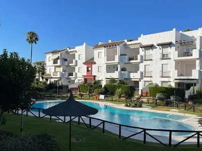 a swimming pool with an umbrella in front of a building at Costa Ballena Unifamiliar in Costa Ballena