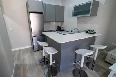 a small kitchen with a counter and stools at Apartamento Cabildo Spa 2 in Sanlúcar de Barrameda