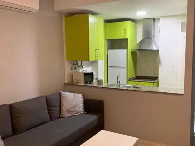a living room with a couch and a kitchen with green cabinets at Apartamento a 5 minutos de la playa de la caleta in Cádiz