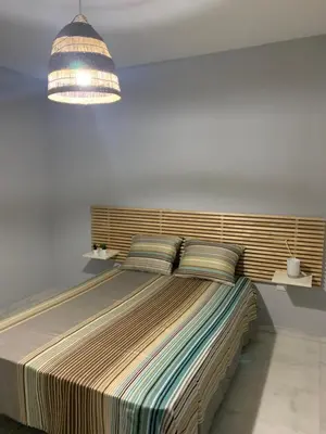 a large bed in a bedroom with a light fixture at Apartamento a 5 minutos de la playa de la caleta in Cádiz