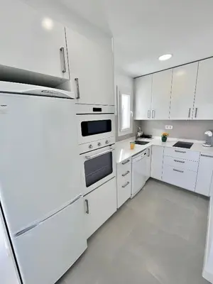 a white kitchen with white appliances and white cabinets at GATU Villa Soleá parking, piscina, pistas tenis, playa de Valdelagrana in El Puerto de Santa María
