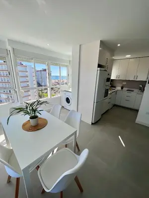 a white kitchen with a white table and chairs at GATU Villa Soleá parking, piscina, pistas tenis, playa de Valdelagrana in El Puerto de Santa María