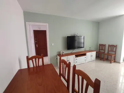 a living room with a dining room table and a flat screen tv at Apartamento Tres Carabelas, AC, Wifi, Parking in Sanlúcar de Barrameda