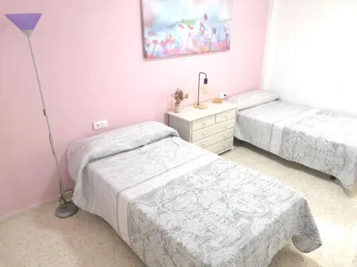 two beds in a room with pink walls at Apartamento Tres Carabelas, AC, Wifi, Parking in Sanlúcar de Barrameda