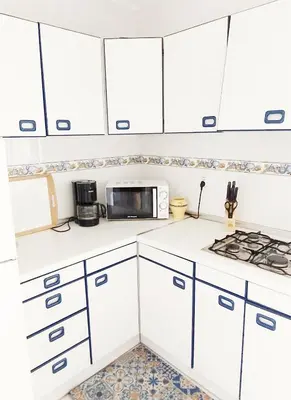 a kitchen with white cabinets and a microwave at Apartamento Tres Carabelas, AC, Wifi, Parking in Sanlúcar de Barrameda